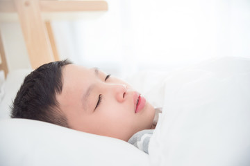 Fototapeta na wymiar Closeup young asian boy sleeping on bed in morning