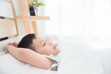 Obraz na płótnie Canvas Young asian boy sleeping on bed in morning