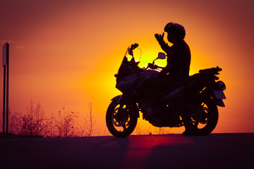 Fototapeta na wymiar silhouette of rider on a motorbike admiring sunset - space for your text