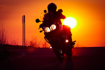 silhouette of rider on a motorbike driving at sunset - space for your text