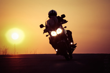 silhouette of rider on a motorbike driving at sunset - space for your text