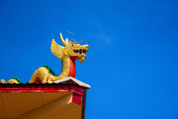 Fototapeta na wymiar Golden dragon statue on the roof of the temple building.