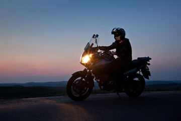 man on his motorbike admiring sunset - summer road trip - space for text