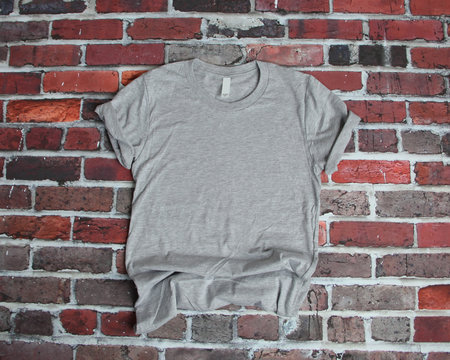 Flat lay mockup of gray tee shirt on brick background