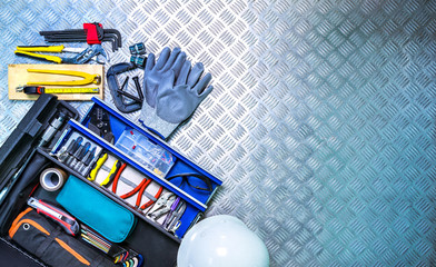 Top view of tools box and helmet on checkered plate background in workshop. Service tools set. Home...