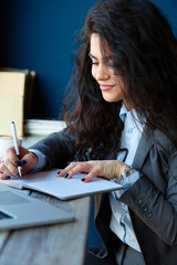 Woman sitting in coffee shop and writing notes