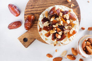 Healthy snack with crisp bread, dates, soft creme cheese, almond and nuts. Easy breakfast close-up on a white background with copy space.