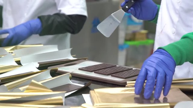 Golden paper wrapped chocolate bars. Process of packaging chocolate in factory