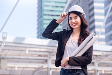 Portrait of Happy professional construction engineer woman holding the blueprint and wearing the safety helmet and glasses at the building site place background,