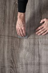 Closeup of male carpenter sticking self-adhesive wooden film