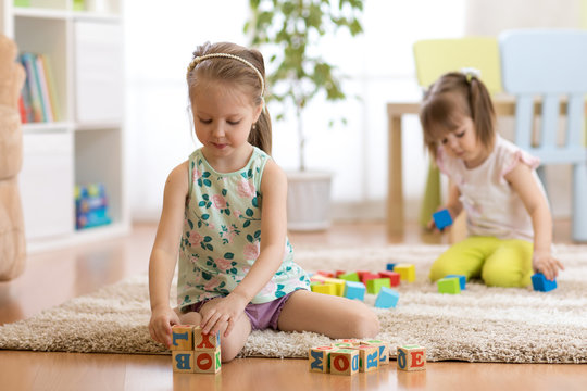 Children kid and toddler girls playing with toys at home, kindergarten or daycare centre.