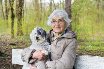 Happy Smiling Senior Woman Hugging her Poodle Dog in a Spring Park