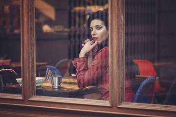 beauty brunette girl behind the window of a restaurant