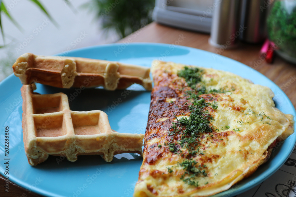 Wall mural breakfast. omelette with herbs and waffles.