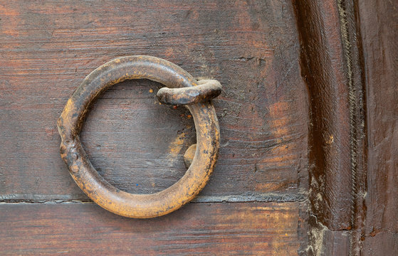 Closeup of rusted ring door knocker over an aged wooden door