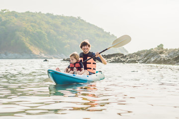 Father and son kayaking at tropical ocean.