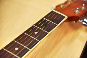 Close up of acoustic guitar classic resting or lying against a wooden background with shallow depth...