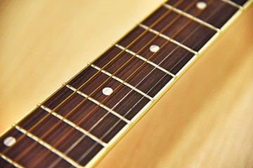 Close up of acoustic guitar classic resting or lying against a wooden background with shallow depth of field. selective focus and vintage tone color.