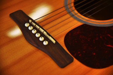 Fototapeta premium Close up of acoustic guitar classic resting or lying against a wooden background with shallow depth of field. selective focus and vintage tone color.
