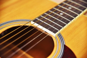 Obraz premium Close up of acoustic guitar classic resting or lying against a wooden background with shallow depth of field. selective focus and vintage tone color.