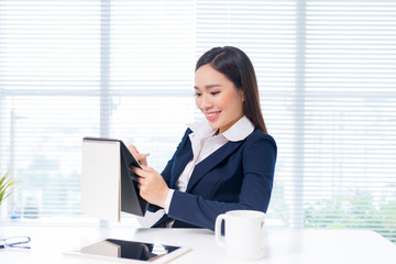 Beautiful young businesswoman sitting at office desk in front of laptop.