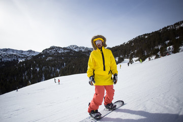 Fototapeta na wymiar Strong and fit professional mountain snowboard rider, rides ski slopes in winter vacation resort, wears bright yellow and red outfit on sunny day. Concept happy active lifestyle holidays