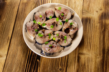 Sliced mackerel with spices on wooden table. Salted scomber on a plate