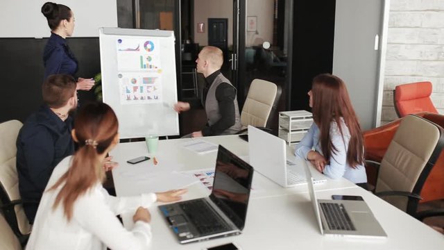 Young woman near whiteboard making presentation about growth of company