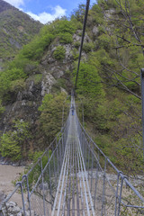 Fototapeta na wymiar Suspension bridge over the river in the mountains