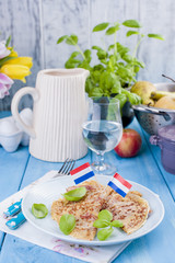 Dutch pancakes with ham for breakfast. Bright colors, blue background. Tasty and caloric. Glass of water and a decanter