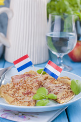 Dutch pancakes with ham for breakfast. Bright colors, blue background. Tasty and caloric