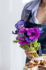 A girl in an apron holds a bouquet of flowers of blue and pink in her hands. Good Morning at home. Place for text