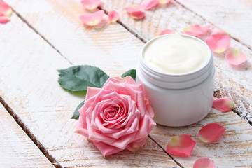 Obraz na płótnie Canvas a care cream in a jar on a wooden background with beautiful roses. anti-aging cream. Cream for skin care. for hands. for face. cosmetics for care. 