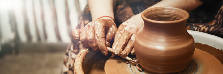 Ceramics. The master on the potter's wheel produces a vessel of clay, undercutting the form. - obrazy, fototapety, plakaty