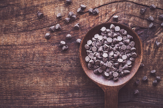 Dark cholocale morsels in a bowl against dark rustic wooden background