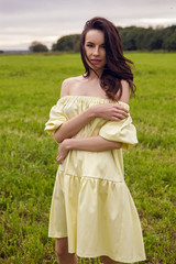 Fototapeta na wymiar woman in yellow dress stands in a field with yellow dry ears of wheat in the summer