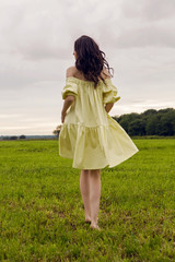 Fototapeta na wymiar woman in yellow dress stands in a field