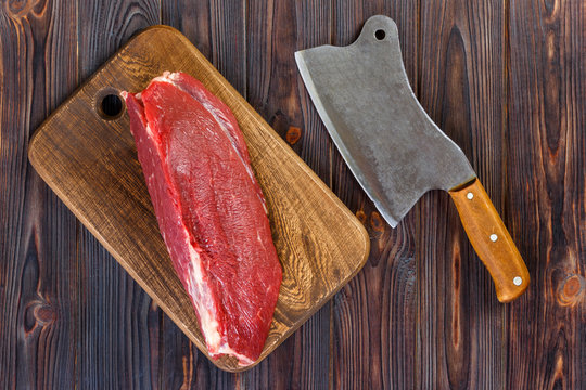 raw beef meat on cutting board with old vintage cleaver