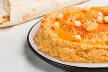 Traditional homemade hummus, with Olive Oil and paprika spices on plate. Jewish Cuisine. Close up. Served with pita.