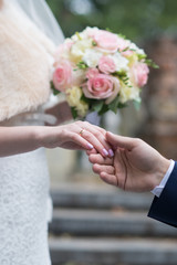 Hands and rings on wedding bouquet