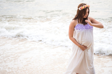 Fototapeta na wymiar Beautiful pregnant woman standing on tropical beach hand touching on belly.