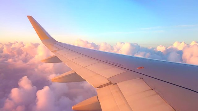 Airplane flight. Wing of an airplane flying above the clouds. View from the window of the plane. Aircraft. Traveling. 4K UHD video footage. 3840X2160