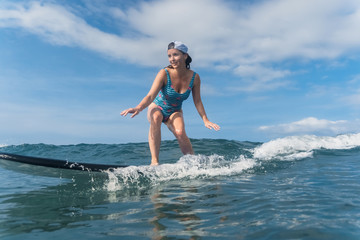 smiling woman in swimming suit surfing in ocean