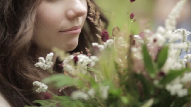 Pretty girl sniffs bouquet tickles nose with plant