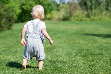 little boy runs along the green grass.