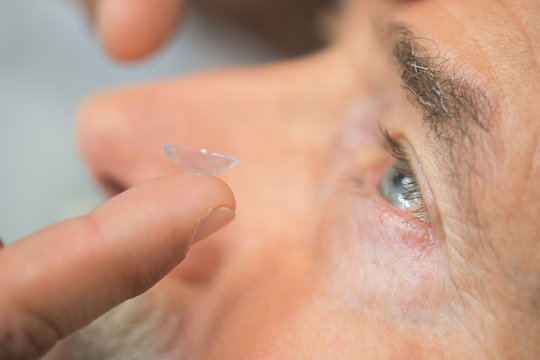 close-up of man putting contact lens in eye