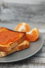 Fresh Toasts with Homemade Orange Jam on Gray Plate over Wooden Background.