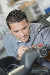 Mechanic working on front of modern scooter