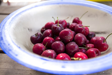 Ripe red cherries inside the transparency blue bowl on the table