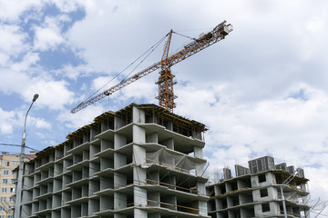 Fototapeta na wymiar Concrete frameworks of buildings and a construction crane above them.